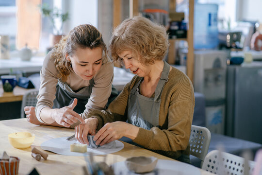 Mother and daughter engage in an art workshop, strengthening their bond through handcraft. Two generations of women take part in a pottery lesson, sharing knowledge and creativity.