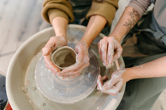 Hands-on learning, senior woman mastering pottery techniques using rotating wheel Mentor teaches pottery fundamentals, demonstrating sculpting skills on an electric wheel