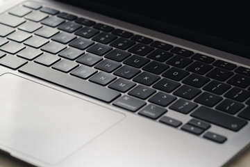 Angled close up of laptop keyboard and screen with light and dark shading