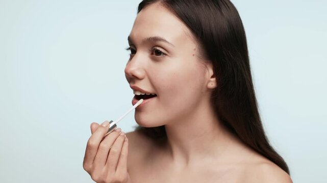 A young female gently applying lip balm on her lips, a daily beauty routine for lip care and hygiene.