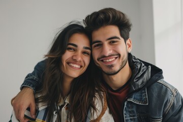 Portrait of a happy latino couple in their 20s wearing a trendy bomber jacket in minimalist or empty room background