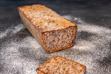 Świeżo upieczony bochenek chleba pełnoziarnistego z kromkami na blacie posypanym mąką. Koncepcja domowego pieczenia, zdrowego odżywiania i rzemieślniczej żywności