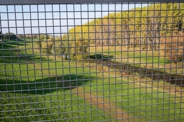 Obraz premium Scenic landscape viewed through metal grid fence 