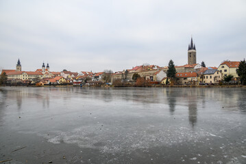 Obraz premium View of Historic old town of Telc, Unesco World Heritage Site, across frozen Ulicky rybnik pond in winter in Czech Republic