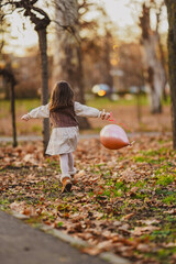 little girl playing in autumn park