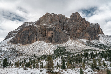 Snow-covered alpine meadows and towering mountains under a dynamic sky. A perfect scene showcasing the raw beauty of winter in the Dolomites.