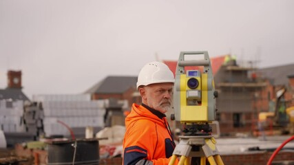 Construction worker using surveying equipment for measurement on site in urban area during overcast day