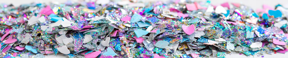 Fototapeta premium Colorful heart-shaped glitter pieces scattered on a white surface, perfect for arts and crafts projects