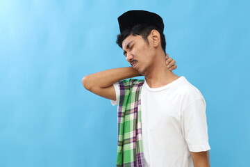 Close up Asian muslim man suffering from neck pain. Isolated on blue with copyspace