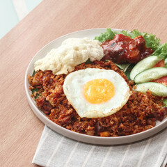 A hearty meal featuring flavorful fried rice topped with a sunny-side-up egg, garnished with fresh cucumber, tomato, and savory sauce