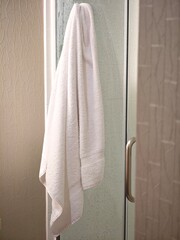 Soft white towel draped elegantly in a stylish bathroom shower at a relaxing spa retreat after a...