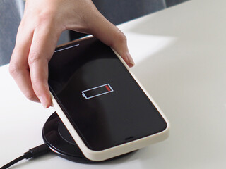 Charging mobile phone battery with wireless charging device in the table. Smartphone charging on a...