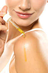 Golden serum droplet cascading from a pipette onto a smooth shoulder and glowing skin, with a soft, confident smile highlighting beauty and care