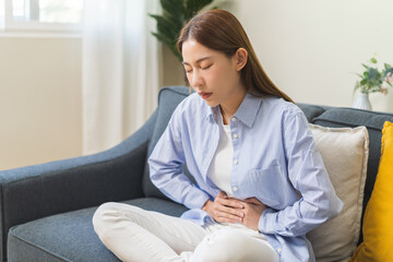 Sick asian young woman in pain, hand holding belly, stomach pain from food poisoning, girl hurt abdomen ache and digestive problem, gastritis or diarrhea. Health care inflammation, abdominal problem