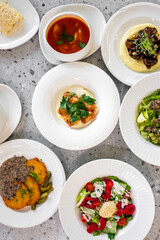 A variety of dishes arranged beautifully on a table, featuring soups, salads, and main courses, highlighting fresh ingredients and vibrant colors, perfect for a culinary showcase.