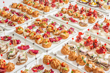 Catering buffet or service with different snacks, appetizers and canapes on a table. Variety of...