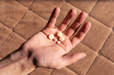 A close-up of a man's hand with five pills in the palm.