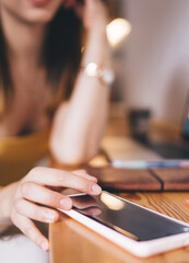 Selective focus on modern smartphone device used by unrecognizable female freelancer checking...
