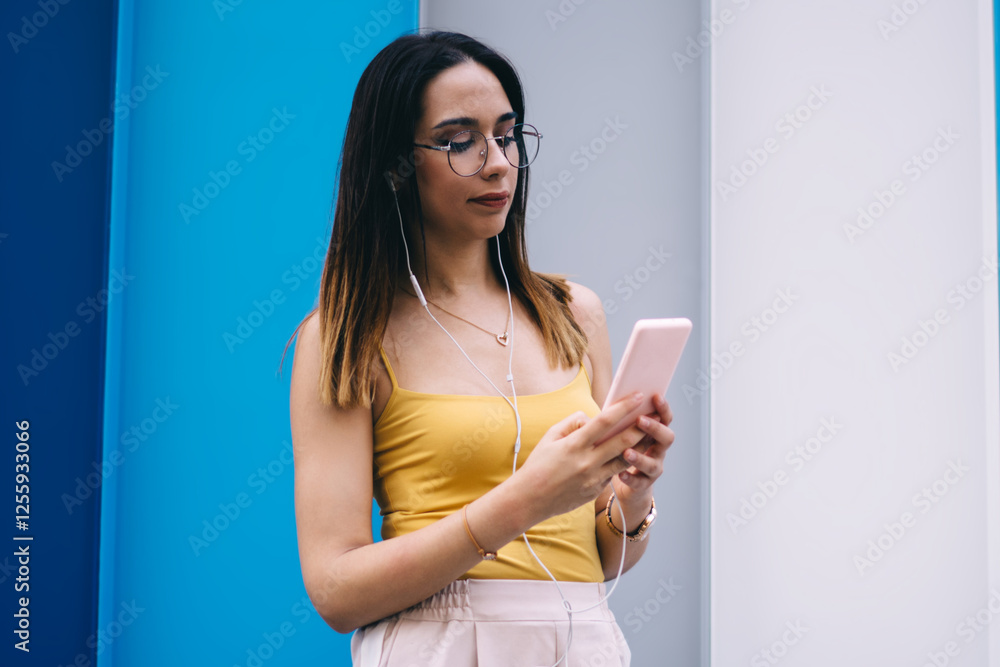 Poster hipster girl in earphones searching audio application for installing to smartphone device using cell