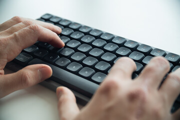 Close up of a man's hands on keyboard of lap top in the dark room, people working at home, modern white notebook. Internet, work, technology concept.
