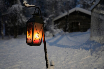 Cozy lantern glowing during a serene polar night in Lapland, with a snowy landscape and rustic cabin in the background. Perfect for capturing the peaceful charm and tranquility of a winter night. © Oleksandr Bochkala