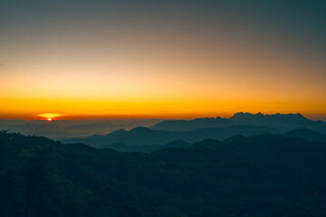 Fototapeta premium High-angle view of a beautiful orange, pink, and yellow sky as the sun rises with copy space on top. Doi Luang Chiang Dao is on the right side, which has an unusual shape. Feeling free and peaceful.