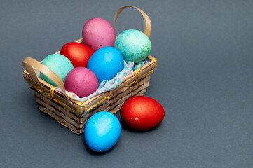 Colored  Easter eggs in small wooden basket on the gray background  ready for Easter