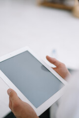 Unrecognizable person using tablet while sitting in room