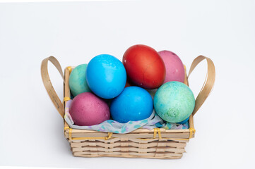 Colored Easter eggs in small wooden basket isolated on the white background.