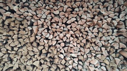 A close-up view of a neat stack of chopped firewood ready to burn, perfect for cozy winter nights.