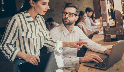 Obraz premium Focused freelancer entrepreneur man woman sit table leader coach girl point monitor laptop collar listen development start-up progress project in workplace workstation