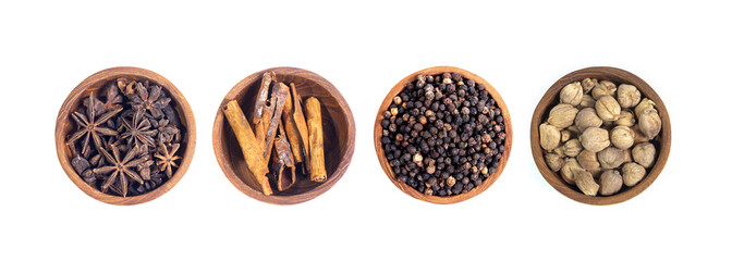 Various spices and herbs, cinnamon, cardamom, star anise and black pepper, in wooden bowl isolated...