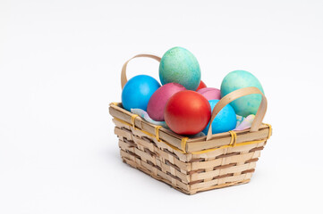 Colored Easter eggs in small wooden basket isolated on the white background.