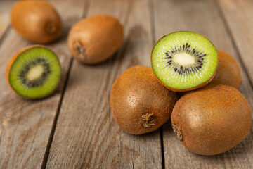 Kiwi on wooden background. Whole fruit and slices pieces of green kiwi on table. fresh ripe juicy kiwi. Tropical fruit. Organic fruit. Healthy eating. Space for text. Copy space.
