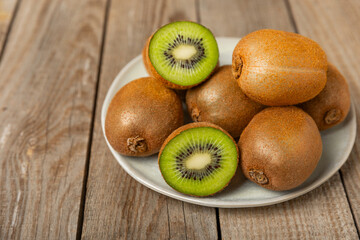 Kiwi on wooden background. Whole fruit and slices pieces of green kiwi on table. fresh ripe juicy kiwi. Tropical fruit. Organic fruit. Healthy eating. Space for text. Copy space.