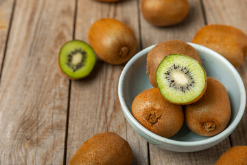 Kiwi on wooden background. Whole fruit and slices pieces of green kiwi on table. fresh ripe juicy kiwi. Tropical fruit. Organic fruit. Healthy eating. Space for text. Copy space.