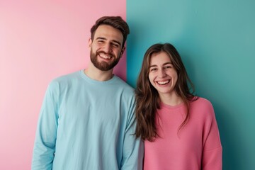 Obraz premium Portrait of a happy caucasian couple in their 20s showing off a lightweight base layer on solid pastel color wall
