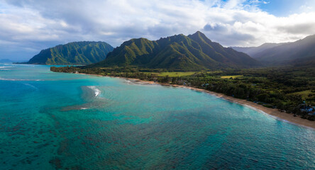 Aerial view of Oahu, Hawaii, showing turquoise waters, a sandy beach, and the lush Ko olau mountain...