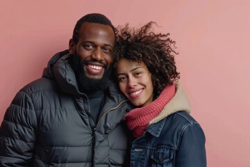 Fototapeta premium Portrait of a smiling multiethnic couple in their 40s donning a durable down jacket in solid pastel color wall