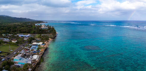 Aerial view of Oahu island's coastline, featuring turquoise waters, coral formations, a residential...