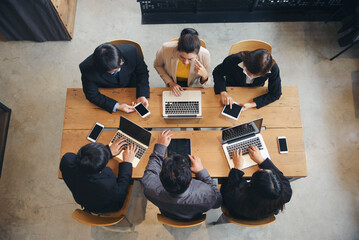 Group of business people plan budget and work via laptop, tablet, and smartphone during brainstorming meeting. Top view of Collaborate with Professional businesswoman and businessman at office