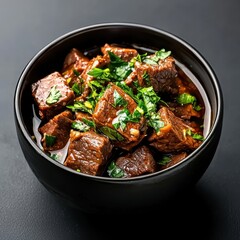 Fototapeta premium Savory rich beef stock in dark ceramic bowl with fresh herbs overhead light three-quarters angle warm culinary delight