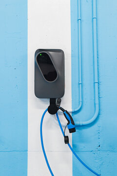 Modern electrical vehicle charging station on blue wall