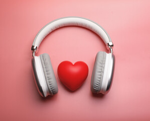headphones embrace a red heart on a soft pink background, symbolizing love for music and emotions. A perfect concept for audio passion, romance, and sound therapy themes.
