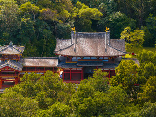 The Byodo In Temple in Oahu, Hawaii, features red wooden structures, a curved tiled roof, and...