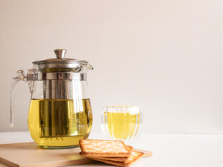 Composition with a glass teapot, cup of tea and crackers on white background. Front view. Aesthetic...