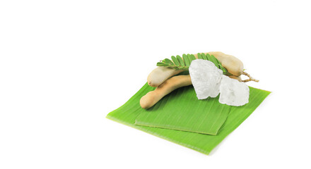 Crystal clear piece of alum and sour tamarinds rest on banana leaves against a white background....
