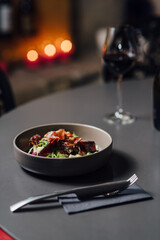 Fresh Gourmet Salad Bowl with Prosciutto and Mixed Greens. Vertical composition with shallow depth of field, soft bokeh of candlelit background