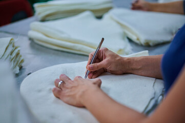 Expert hands meticulously assessing felt products for quality in a bustling workshop filled with...