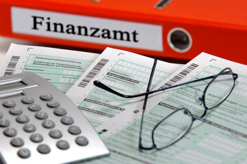 Vor einem Aktenordner mit Beschriftung Finanzamt liegen Formulare für die Steuererklärung - obrazy, fototapety, plakaty